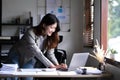 Happy young Asian businesswoman standing using calculator and laptop computer at office. Royalty Free Stock Photo