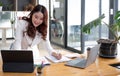 Happy young Asian businesswoman standing using laptop computer at office. Royalty Free Stock Photo