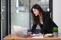 Happy young Asian businesswoman standing using laptop computer at office. Royalty Free Stock Photo