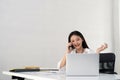 Happy young asian businesswoman talk on the mobile phone and smile while sitting at working place in office Royalty Free Stock Photo