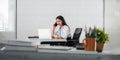 Happy young asian businesswoman talk on the mobile phone and smile while sitting at working place in office Royalty Free Stock Photo