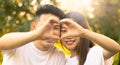 Happy young asian couple make heart sign with hands at the park