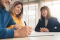 Happy young Asian couple and realtor agent. Cheerful young man signing some documents while sitting at desk together with his wife Royalty Free Stock Photo