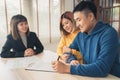 Cheerful young man signing some documents while sitting at desk together with his wife. Royalty Free Stock Photo