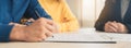 Happy young Asian couple and realtor agent. Cheerful young man signing some documents while sitting at desk together with his wife Royalty Free Stock Photo