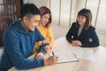 Cheerful young man signing some documents while sitting at desk together with his wife. Royalty Free Stock Photo