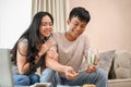 A happy young Asian couple is saving some money in a jar while talking about their savings plan Royalty Free Stock Photo