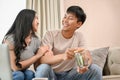 A happy young Asian couple is saving some money in a jar while talking about their savings plan Royalty Free Stock Photo