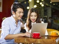 Young asian couple using laptop in coffee shop Royalty Free Stock Photo