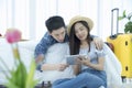 Happy young Asian couple tourists with tablet computer. Couple packing suitcase on bed and lying and looking digital tablet for Royalty Free Stock Photo