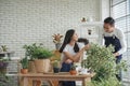 Happy young Asian couple wearing apron uniforms gardening and take care of their plants together