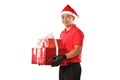 Happy young Asian delivery man in red uniform, Christmas hat carry boxes of presents in hands isolated on white background during