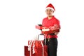 Happy young Asian delivery man in red uniform, Christmas hat carry boxes of presents in hands isolated on white background during