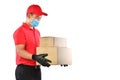 Happy young Asian delivery man in red uniform, medical face mask, protective gloves carry cardboard box in hands isolated on white