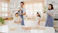 Happy young Asian family with preschool kids have fun listen to music and dancing while cooking baking pastry for breakfast meal Royalty Free Stock Photo