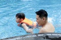 Happy young Asian father and little boy son with life jacket in blue water pool, dad teaching child to swimming, kid learn how to Royalty Free Stock Photo