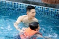 Happy young Asian father and little boy son with life jacket in blue water pool, dad teaching child to swimming, kid learn how to Royalty Free Stock Photo