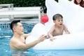 Happy young Asian father and little boy son with white swan plastic toy in blue water pool, dad teaching child kid to swimming, Royalty Free Stock Photo