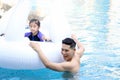 Happy young Asian father and little girl daughter with white swan plastic toy in blue water pool, dad teaching child kid swimming Royalty Free Stock Photo