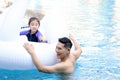 Happy young Asian father and little girl daughter with white swan plastic toy in blue water pool, dad teaching child kid swimming Royalty Free Stock Photo