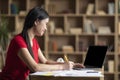 Happy young asian female student watching online lesson on laptop with empty screen in cabinet Royalty Free Stock Photo