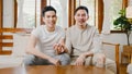 Happy young asian gay couple sit couch use smartphone facetime video call with friends and family in living room at home. Stay at Royalty Free Stock Photo