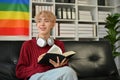 A happy young Asian gay man is daydreaming while reading a book on the sofa Royalty Free Stock Photo