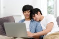Happy young asian gay man couple using laptop computer while sitting onsofa at home, homosexual and lgbt with technology lifestyle Royalty Free Stock Photo