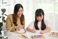 Happy young Asian girl drawing and painting with water colors with her mom Royalty Free Stock Photo