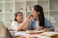 A happy young Asian girl is enjoying studying English with a teacher at home Royalty Free Stock Photo