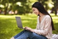 Happy young asian girl freelancer working on laptop computer in park Royalty Free Stock Photo