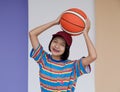 Happy young asian girl palying basketball with pastel background