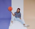 Happy young asian girl palying basketball with pastel background