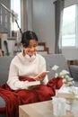 Happy young girl sitting on sofa in living room and using mobile phone. Royalty Free Stock Photo