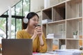 Happy young asian girl with wireless headphones looking at laptop screen, reading listening online courses, studying Royalty Free Stock Photo