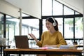 Happy young asian girl with wireless headphones looking at laptop screen, reading listening online courses, studying Royalty Free Stock Photo