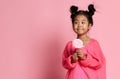 Happy young asian little girl kid lick eat happy big sweet lollypop candy on pink Royalty Free Stock Photo