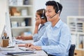 Happy young asian male call centre telemarketing agent talking on a headset while working on a computer in an office Royalty Free Stock Photo