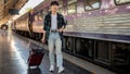 A happy young Asian man with a backpack and a luggage catching the train at a railway station Royalty Free Stock Photo