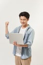 Happy young Asian man carrying laptop computer and raising his fist doing yes gesture isolated on white background Royalty Free Stock Photo