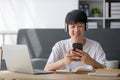 A happy young Asian man in casual clothes is looking out the window and daydreaming about his happiness while sitting on Royalty Free Stock Photo