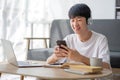 A happy young Asian man in casual clothes is looking out the window and daydreaming about his happiness while sitting on Royalty Free Stock Photo