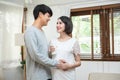 Happy young asian man going to be father stand side and look at woman with smile. Happy mature man leaning to his pregnant wife