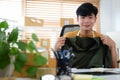 Happy young asian man online seller sitting at his home office and smiling to camera