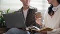 A happy young Asian man and a pretty girl are working on a laptop together, working on a co-project, sharing ideas and Royalty Free Stock Photo