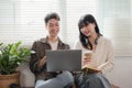 A happy young Asian man and a pretty girl are working on a laptop together, working on a co-project, sharing ideas and Royalty Free Stock Photo