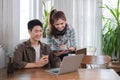 A happy young Asian man and a pretty girl are working on a laptop together, working on a co-project, sharing ideas and Royalty Free Stock Photo