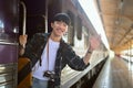 Happy young Asian man waving hand from the train while leaving the station. Traveling concept Royalty Free Stock Photo