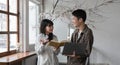 A happy young Asian man and a pretty girl are working on a laptop together, working on a co-project, sharing ideas and Royalty Free Stock Photo