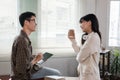 A happy young Asian man and a pretty girl are working on a laptop together, working on a co-project, sharing ideas and Royalty Free Stock Photo